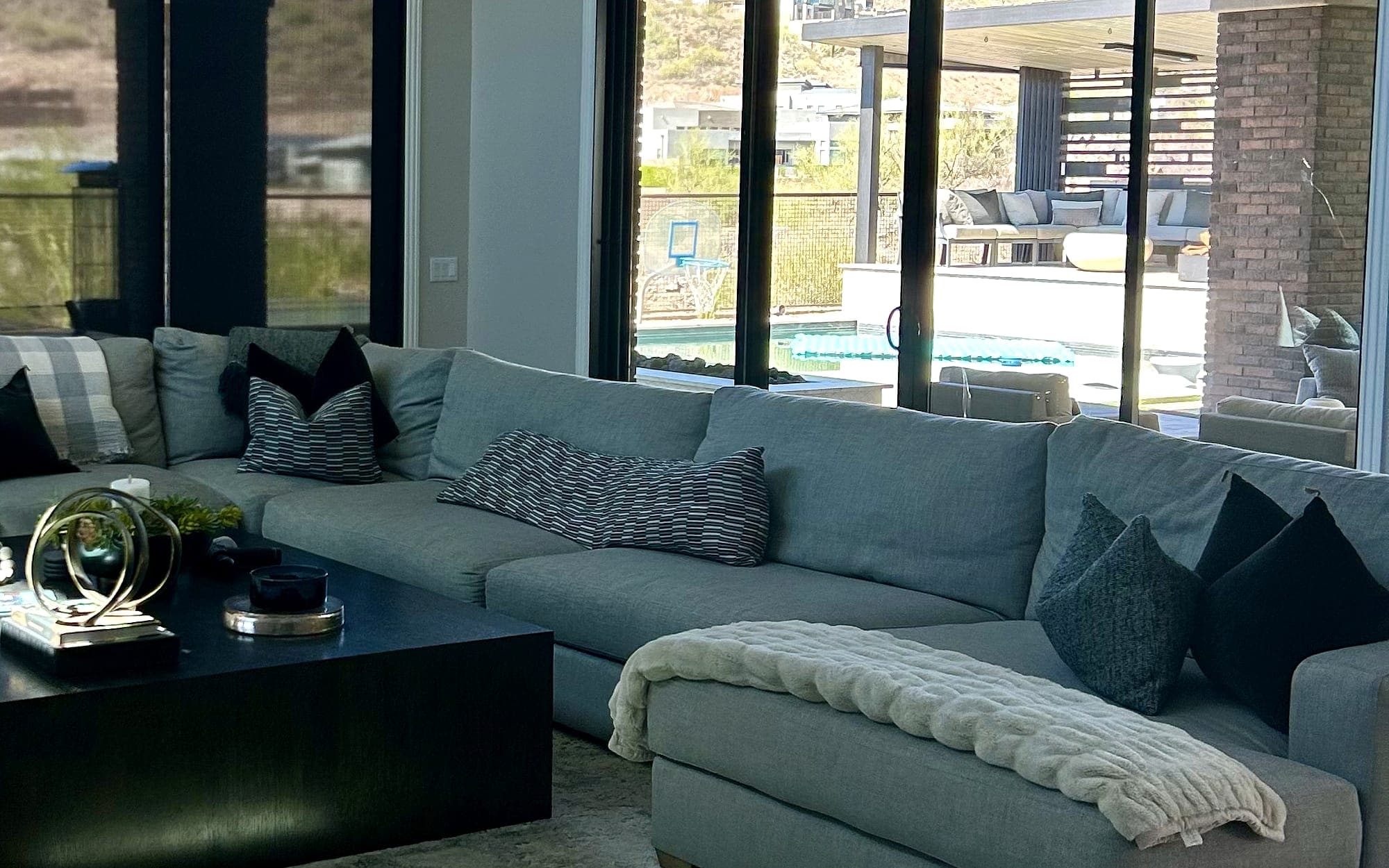 Reference photo of a bright, tidy living room opening onto a pool in daylight